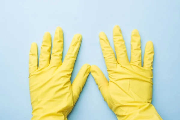 Tangan di sarung tangan kuning untuk membersihkan latar belakang biru. Konsep pembersihan rumah. Tampilan atas — Stok Foto