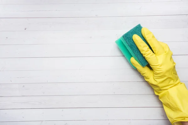 Tangan di sarung tangan kuning dan spons pembersih untuk membersihkan di latar belakang kayu. Konsep pembersihan rumah. Tampilan atas, ruang penyalinan — Stok Foto