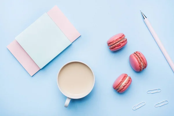 Konzept Frühstück. Tasse Kaffee, Makronenplätzchen und Notizblock auf blauem Pastellgrund. flache Verlegestile. — Stockfoto