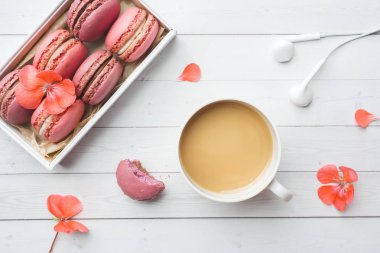 Bir fincan kahve, bir kutuda makarna kurabiyesi, beyaz arka planda çiçekler. kopya alanı. kavram güzel Kahvaltı. düz yatıyordu