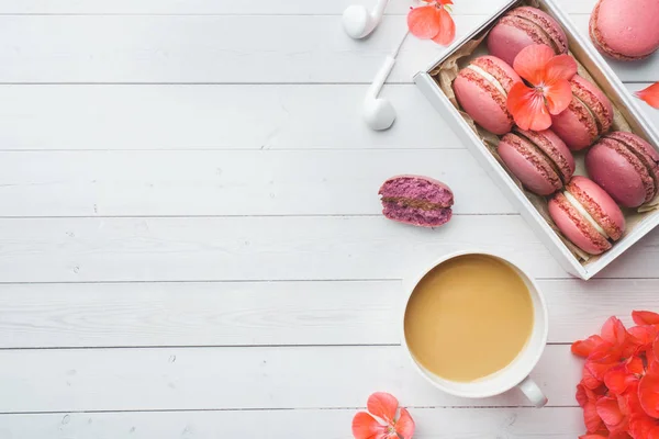 Taza de café, galletas de macarrones en una caja, flores sobre un fondo blanco. espacio de copia. concepto hermoso desayuno. plano laico — Foto de Stock