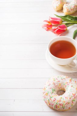 Çay ve çörekler Fincan, kopya alanı ile beyaz masada çiçek lale.