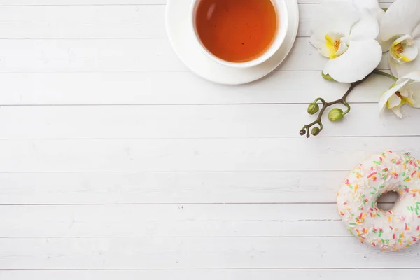 Taza de té y rosquillas, orquídea blanca sobre mesa blanca con espacio para copiar. Piso tendido, vista superior . — Foto de Stock