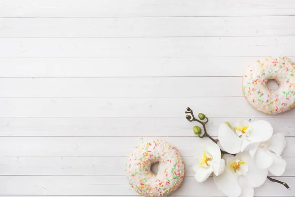 Donuts y orquídea blanca en la mesa blanca con espacio de copia. Piso tendido, vista superior . — Foto de Stock