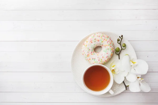 Taza de té y rosquillas, orquídea blanca sobre mesa blanca con espacio para copiar. Piso tendido, vista superior . — Foto de Stock