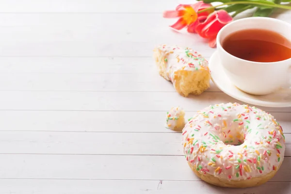 Taza de té y rosquillas, tulipanes de flores sobre mesa blanca con espacio para copiar . — Foto de Stock