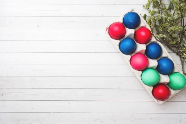 Colorful Easter eggs in paper boxes on a white table. Copy space. — Stock Photo, Image