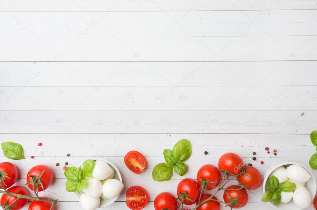 The ingredients for a Caprese salad. Basil, mozzarella balls and tomatoes on a white background with copy space.