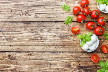Caprese salatası için malzemeler. Fesleğen, mozzarella topları ve kopya alanı ile ahşap bir arka plan üzerinde domates.