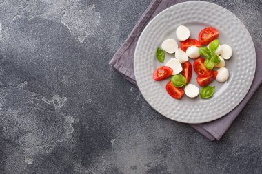 Domates Caprese salatası, mozzarella peyniri ve fesleğen koyu bir arka plan üzerinde. İtalyan mutfağı. Kopyalama alanı
