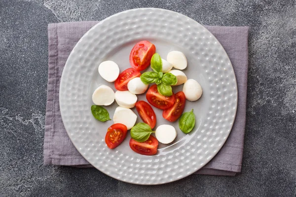 Domates Caprese salatası, mozzarella peyniri ve fesleğen koyu bir arka plan üzerinde. İtalyan mutfağı.