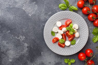 Domates Caprese salatası, mozzarella peyniri ve fesleğen koyu bir arka plan üzerinde. İtalyan mutfağı. Kopyalama alanı