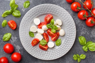 Domates Caprese salatası, mozzarella peyniri ve fesleğen koyu bir arka plan üzerinde. İtalyan mutfağı.