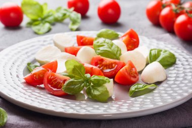 Domates Caprese salatası, mozzarella peyniri ve fesleğen koyu bir arka plan üzerinde. İtalyan mutfağı.