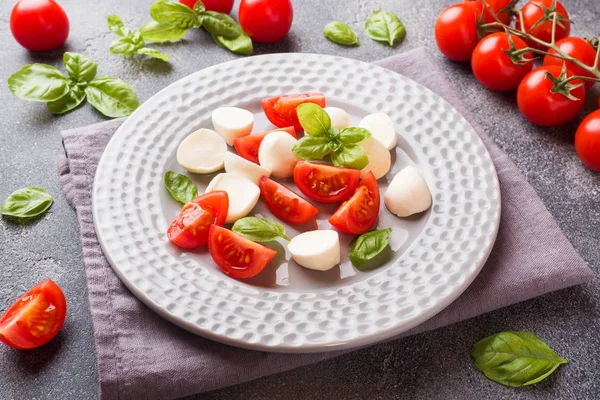 Caprese salade de tomates, fromage mozzarella et basilic sur un fond sombre. Cuisine italienne . — Photo