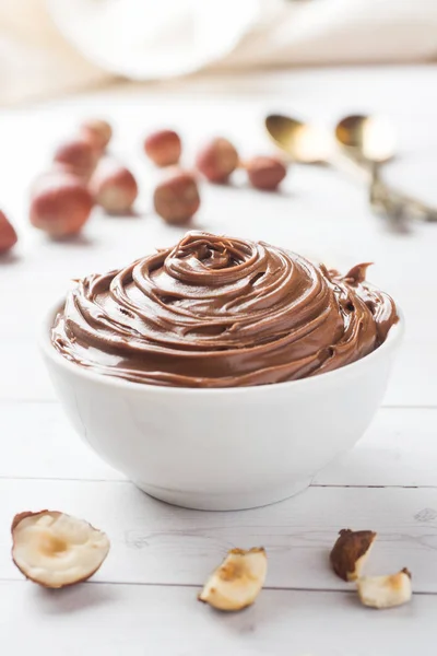 Nougat nut chocolate in a plate on a white background with hazelnut nuts. Concept of Breakfast.