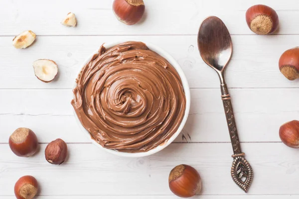 Nougat nut chocolate in a plate on a white background with hazelnut nuts. Concept of Breakfast.