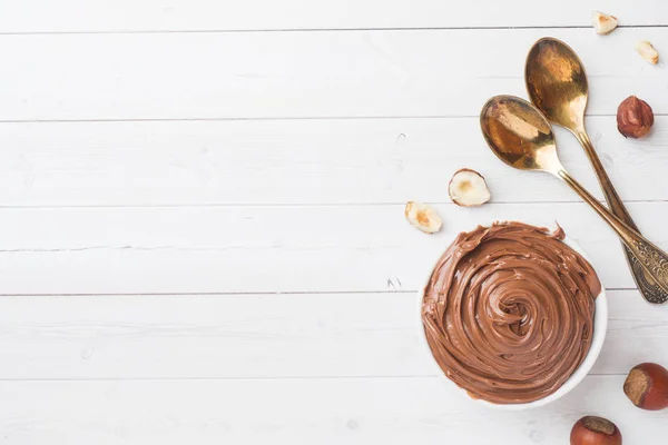 Nougat nut chocolate in a plate on a white background with hazelnut nuts. Concept of Breakfast. Copy space.