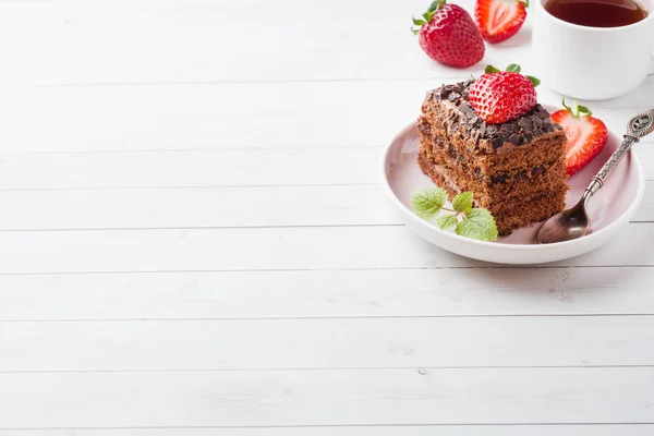 Truffle cake with chocolate and strawberries and mint on a white wooden table. Selective focus. Copy space