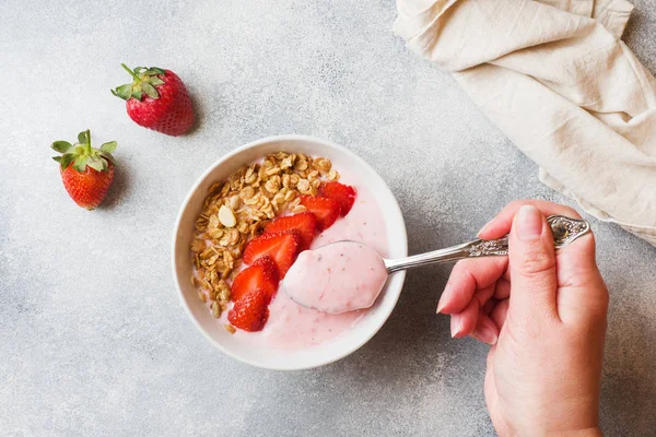 Taze çilek ve müsli ile ev yapımı yoğurt. Sağlıklı bir kahvaltı kavramı. Eller çekimde.