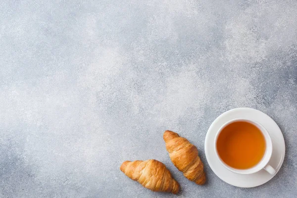 Taza de té y croissant sobre un fondo de hormigón gris con espacio para copiar. Concepto mañana Desayuno . — Foto de Stock