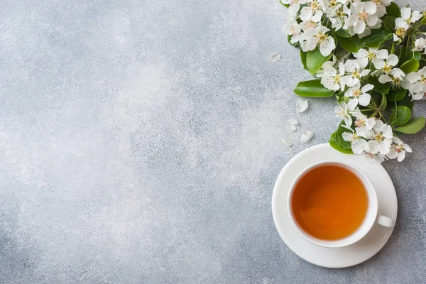 Taza de té y florecimiento rama de Apple sobre un fondo de hormigón gris con espacio de copia. Concepto mañana Desayuno . — Foto de Stock