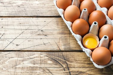 Rustik ahşap arka plan üzerinde fabrika ambalaj kahverengi çiğ yumurta. Kopyalama alanı