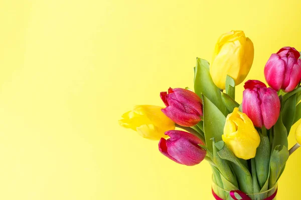 Ramo de tulipanes amarillos y rosados sobre fondo amarillo. Copiar espacio —  Fotos de Stock