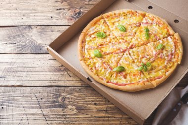 Tahta bir masa üzerinde bir karton kutu içinde taze pişmiş pizza. Kopyalama alanı