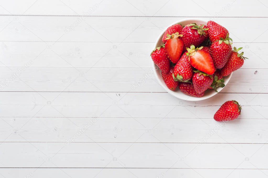 Fresh strawberries in a ceramic plate on a white table. Copy space.