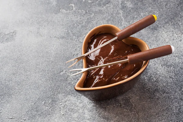 Chocolate paste with cinnamon and anise. Fondue with chocolate on a dark concrete table.