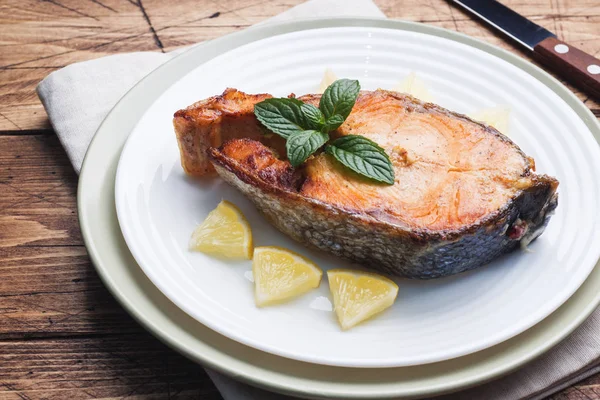 Стейк запеченный лосось рыбы на тарелке с лимоном. Деревянный стол . — стоковое фото