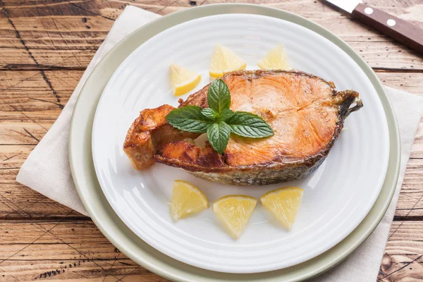 Стейк запеченный лосось рыбы на тарелке с лимоном. Деревянный стол . — стоковое фото