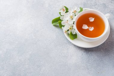 Fincan çay ve kopya alanı ile gri bir beton arka plan üzerinde apple şube çiçeklenme. Konsept sabah Kahvaltısı.