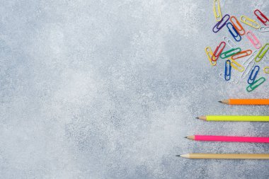 Gri masada parlak renkli kalemler ve ataçlar. okul kavramı.