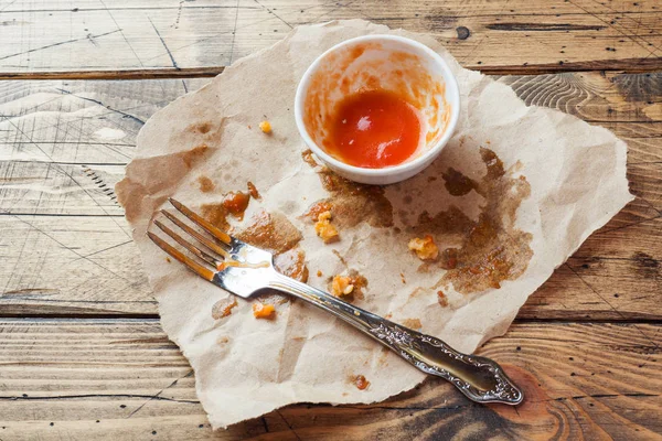 Dirty dishes after meals in oil and tomato sauce. Leftover food after eating chicken nuggets and sauce. Wooden background.