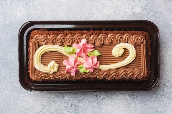 Pastel rectangular de chocolate decorado con rosas crema. La comida dulce es un negocio de confitería. Vista superior — Foto de Stock
