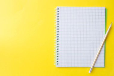 Sunum, yazar veya okul eğitimi, blogger, roman ve sürtünme veya marka hikayesi konsepti için sarı masa arka plan üzerinde kopya alanı ile temiz beyaz defter ve kalem.