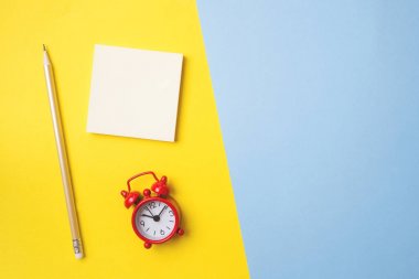 Çıkartmalar kırtasiye ve alan bir kopyası ile sarı mavi bir masa üzerinde bir saat. Kavram okul eğitimi, ofis ve serbest.
