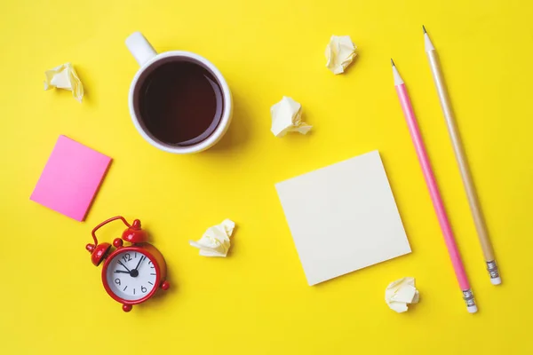 Διαφορετικά επιστολόχαρτα, ένα φλιτζάνι καφέ και ένα ρολόι σε ένα κίτρινο τραπέζι με ένα αντίγραφο του χώρου. Σχολική εκπαίδευση, γραφείο και ελεύθερος επαγγελματίας. — Φωτογραφία Αρχείου