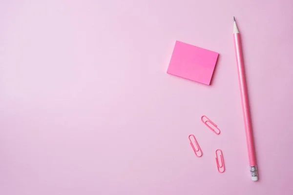 Pinza de bloc de notas rosa y lápiz sobre fondo rosa con espacio para copiar. Concepto educación escolar, oficina y freelancing . — Foto de Stock