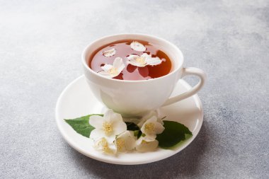 Kopya alanı ile gri bir masada Yasemin çiçekleri ile çay Fincan.