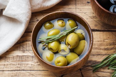 Ahşap masa üzerinde ahşap kasesiyah ve yeşil zeytin. Metin için alanla en iyi görünüm.