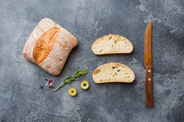 Italienisches Ciabatta-Brot mit Oliven und Rosmarin auf dunklem Betongrund. Kopierraum — Stockfoto