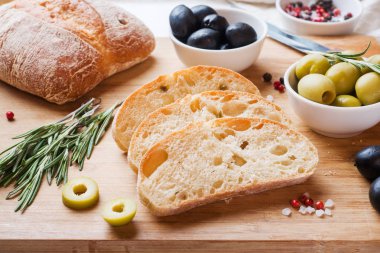 Ahşap bir Tahta üzerinde zeytin ve biberiye ile İtalyan ciabatta ekmek.