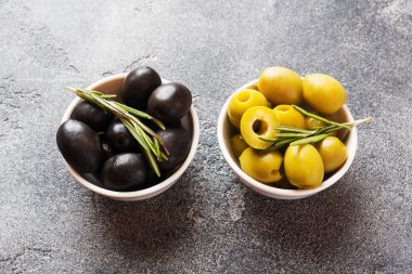 Koyu masaüzerinde kaselerde siyah ve yeşil zeytin. Kopyalama alanı.