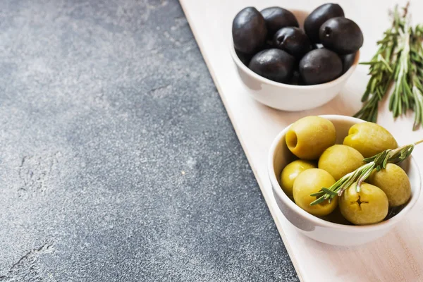 Olives noires et vertes dans des bols sur la table noire. Espace de copie . — Photo