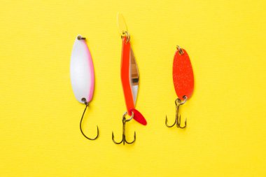Balık kancaları ve yemler kopya alanı ile sarı bir arka plan üzerinde farklı balık yakalamak için bir dizi. Düz yatıyordu