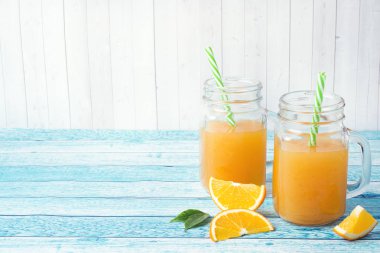 Cam Kavanoz ve mavi bir arka plan üzerinde taze portakal portakal suyu.