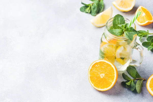 Limonata bardak maden suyu, limon ve nane kavanoza ışık arka plan üzerinde bırakır. Kopya alanı